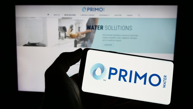 Stuttgart, Germany - 03-22-2023: Person holding cellphone with logo of US company Primo Water Corporation on screen in front of business webpage. Focus on phone display.