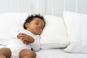 black african american baby sleeping on a white mattress.