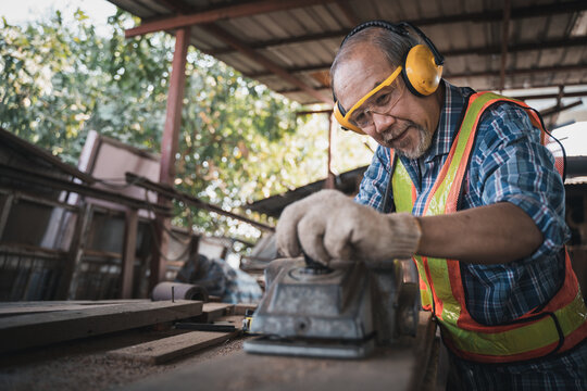 An elderly carpenter works the wood with meticulous care.