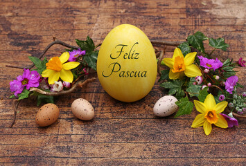 Feliz tarjeta de felicitación de Pascua: Huevo de Pascua con letras con el texto Feliz Pascua en madera rústica con narcisos y ramitas