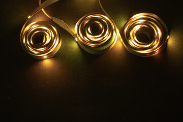 A stack of LED lights on coiled flexible lighting strips, colored yellow.