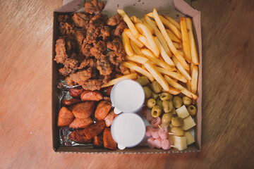 Top view of a box of assorted snacks on a wooden table.