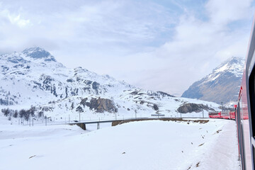 Fototapeta na wymiar Bernina mountain pass. The famous red train is crossing the white lake. Amazing landscape of the Switzerland land. Famous destination and tourists attraction