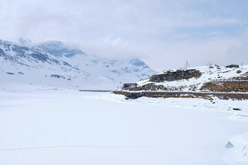 Bernina mountain pass. The famous red train is crossing the white lake. Amazing landscape of the Switzerland land. Famous destination and tourists attraction