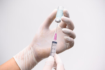 Close up doctor's hand holding medicine bottle and syringe for vaccine to patient on blue tone background.Nurse using syringe are vaccination to patient for influenza protection.Medication concept.