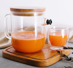 Hot drink from a sea-buckthorn in a glass cup and jug