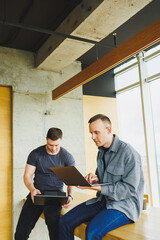 Work of two colleagues sitting together while exchanging ideas with a laptop in a meeting room and analyzing work charts. Work in a modern, spacious office