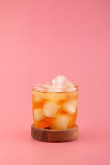 Glass of Apple spritzer or Apfelschorle on pink background. Cold carbonated apple juice. Homemade spritzer served with ice. Sparkling drink.