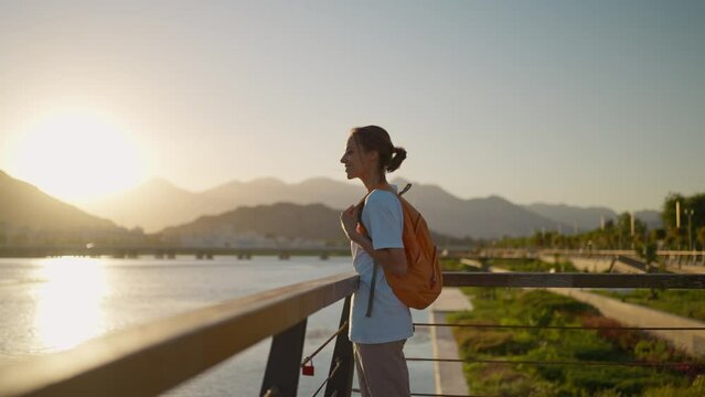 Woman traveler standing and watching the sunset or sunrise with mountains and sea view. Back view