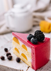 A slice of a pink strawberry cheesecake served with fresh berries on a white board