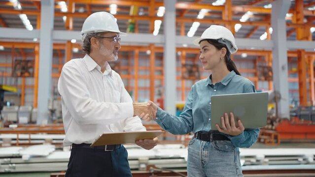 Two engineer manager leader and woman assistant holding laptop and shaking hands for making together after processes order at metal factory