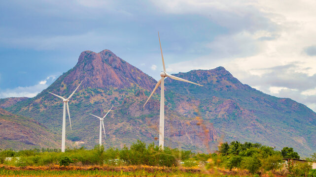 Windmill - Wind turbine below the mountain on the agriculture land. Alternate energy source generator with environment friendly. Wind turbines for ecological power supply ..