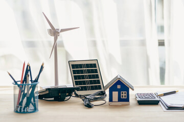 Wind turbines and solar cells. House on the table. Renewable energy concept.