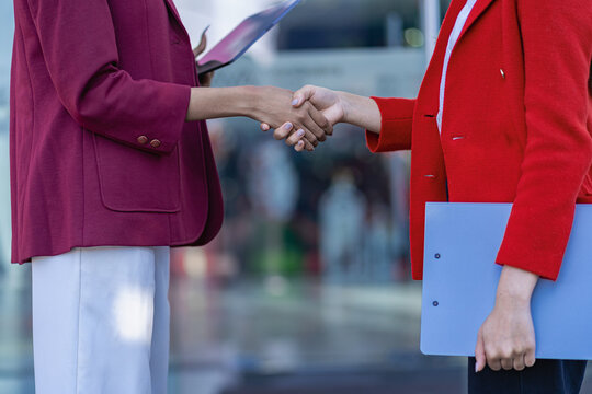 two young female accountants shaking hands successful business negotiations with female partner city glass office background Teamwork and successful management concept