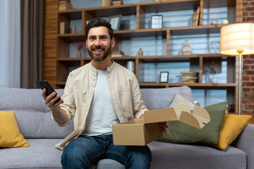 Portrait of happy online shopper at home, mature adult man smiling and looking at camera, holding...