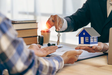 Handing over house keys and introducing houses Sales representatives handing over keys to customers New home buyers are approved home loans and insurance contracts.