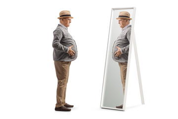 Full length profile shot of a senior man with a big belly standing in front of a mirror
