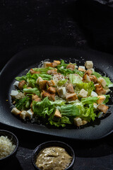 Caesar salad on a black plate close-up