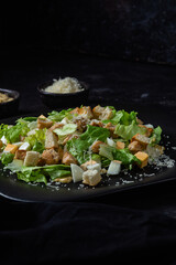 Caesar salad on a black plate close-up