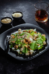 Caesar salad on a black plate close-up