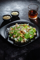 Caesar salad on a black plate close-up