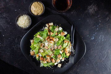 Caesar salad on a black plate close-up
