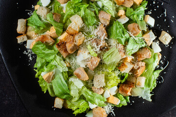 Caesar salad on a black plate close-up