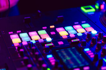 Obraz na płótnie Canvas Close up of DJ mixing console in party light