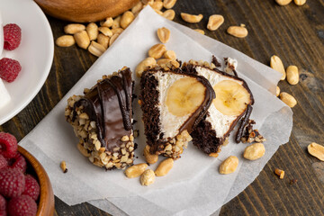 Sliced sweet cake with banana, chocolate glaze, milk filling and peanuts