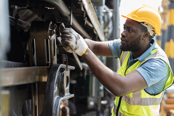 Male engineer maintenance locomotive engine, wearing safety uniform, helmet and gloves in...