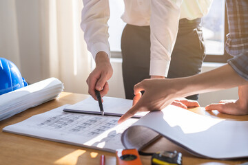 Builder team, hand of asian, caucasian young engineer, architect two man are discussing construction drawing on blueprint follow project to build an industrial plan at site. Engineering worker people.