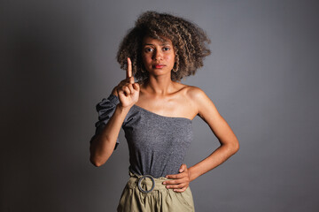 black woman with raised finger indicating attention, fight against racism and violence against...
