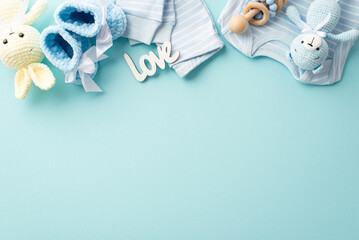 Baby accessories concept. Top view photo of infant clothes blue shirt pants inscription love knitted booties wooden rattle teddy bear and bunny toys on isolated pastel blue background with empty space - obrazy, fototapety, plakaty