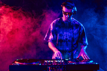 Club DJ playing music at party wearing sunglasses