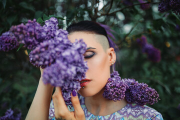 Portrait of an informal brunette girl in lilac bloom. View of girl in lilac garden outdoors