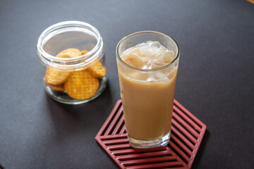 Iced coffee and biscuits in a transparent glass on a black background