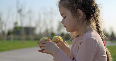 Two cute girls eating apples outdoor