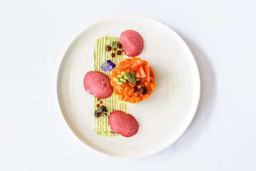 Salmon tartare with strawberries on a white plate