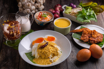 Rice noodles with fish coconut milk curry sauce and spicy curry sauce, southern style with vegetables set, fried chicken, boiled egg and pickled vegetables, Thai traditional style. 
