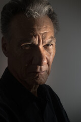 Obraz premium Dark Moody Portrait of an older man in low light wearing a black shirt