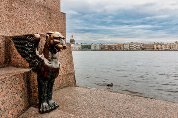 Sculpture of Griffin - bronze winged lions 1834 on the University Embankment of the Neva river with the background view of Isaac Cathedral, Saint-Petersburg, Russia - obrazy, fototapety, plakaty