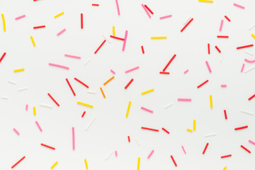 flat lay of colorful sprinkles over white background, festive decoration for banner, poster, flyer,...