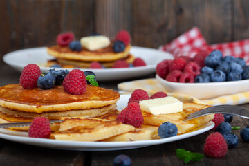 American pancakes with fresh blueberry, raspberry and honey served on white plate. Healthy morning breakfast. Wooden background.