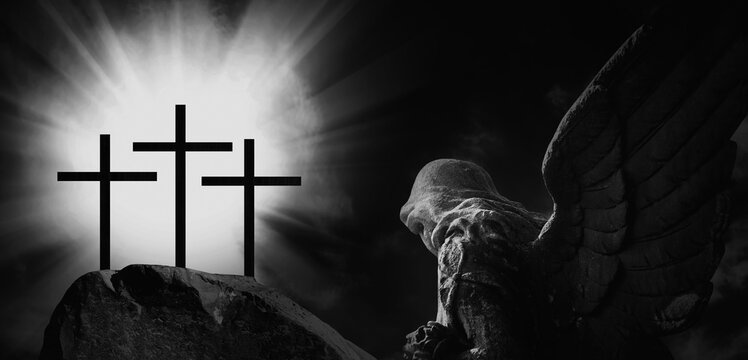 Angel and silhouette of three crosses on a rocky hill against dramatic sky background and symbolize the Crucifixion of Christ. Black and white image.
