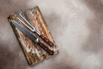 meat knife and barbecue fork on old board on concrete background. ingredients for grilling meat...