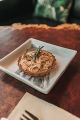 Closeup of small tart almond slice served on wooden table in the cafe.