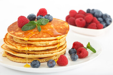 American pancakes with fresh blueberry, raspberry and honey. Healthy morning breakfast. White background.