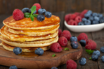 American pancakes with fresh blueberry, raspberry and honey served on white wooden board. Healthy morning breakfast.
