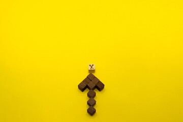 上向きの茶色い矢印のウッドキューブの上でエールを送る黄色い背景