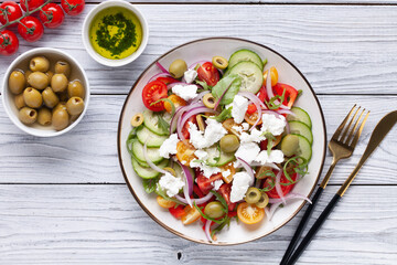 Greek salad of fresh cucumber, tomato, sweet pepper, arugula, red onion, feta cheese and olives with olive oil. Healthy food. Top view